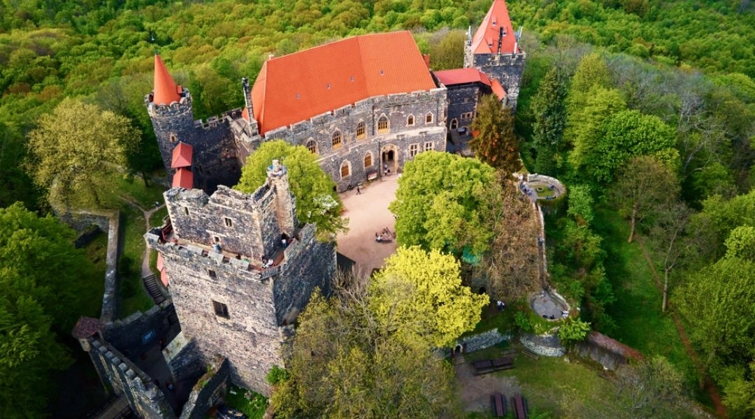 Widok z lotu ptaka na Zamek Grodziec z kamiennymi murami, dziedzińcem i zielonym otoczeniem.