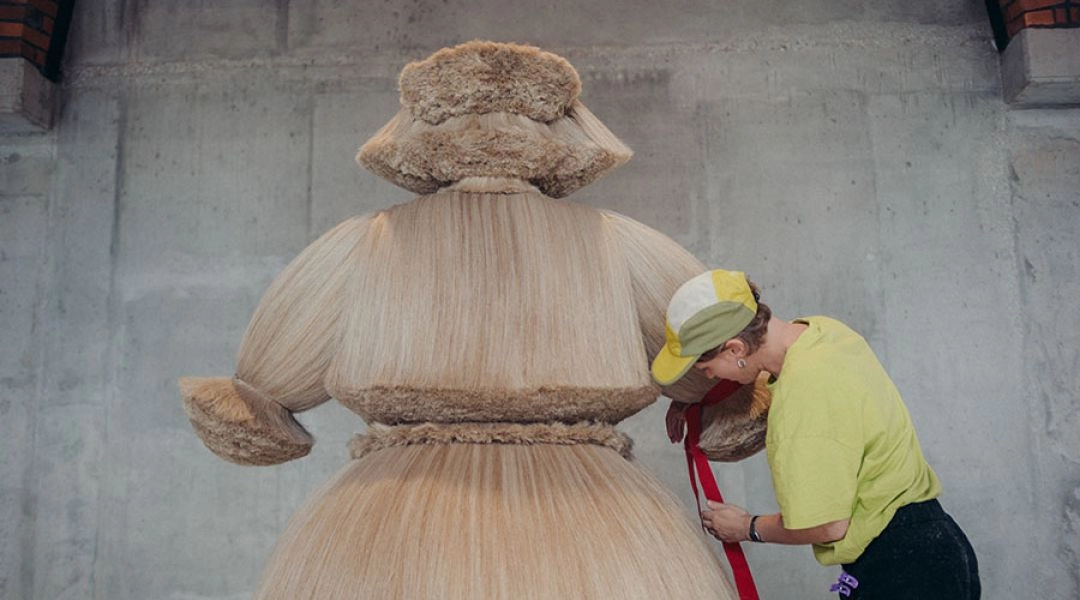 Artystka poprawia dużą miękką formę z jasnych włókien na wystawie Ali Savashevich w Muzeum Etnograficznym we Wrocławiu.