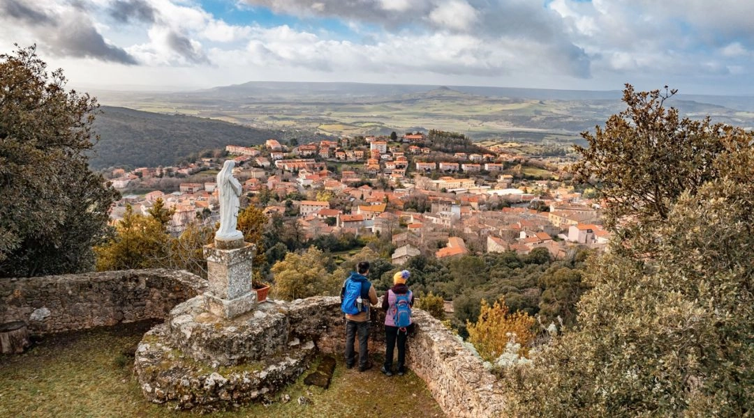 Widok na Laconi z punktu widokowego, z rzeźbą i rozległą panoramą sardyńskich wzgórz.