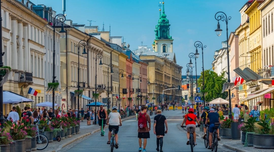 Krakowskie Przedmieście w Warszawie latem, spacerowicze i rowerzyści na ulicy
