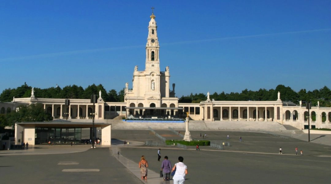Pielgrzymi idący na kolanach przez plac sanktuarium w Fatimie w stronę bazyliki.