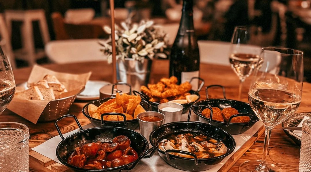 stolik w restauracji Pablo’s Tapas w Warszawie z talerzami tapas, winem i nastrojowym oświetleniem