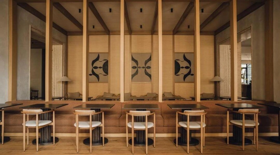 Wnętrze restauracji w hotelu PURO Warszawa Stare Miasto z drewnianymi kolumnami i minimalistycznym wystrojem.