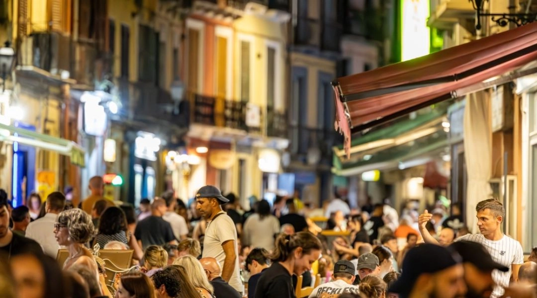 Tłum gości siedzących wieczorem przy restauracyjnych stolikach na jednej z ulic Sardynii.