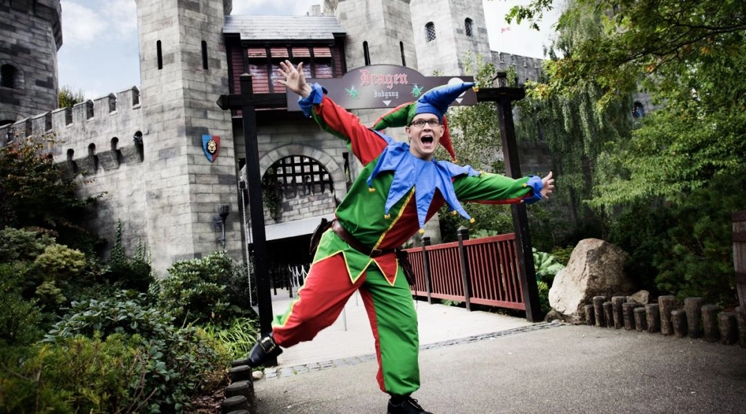 Animator w kolorowym stroju przed zamkiem w strefie rycerskiej Legolandu w Billund