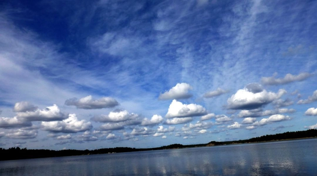 Chmury odbijające się w spokojnej tafli wody na szwedzkim archipelagu.