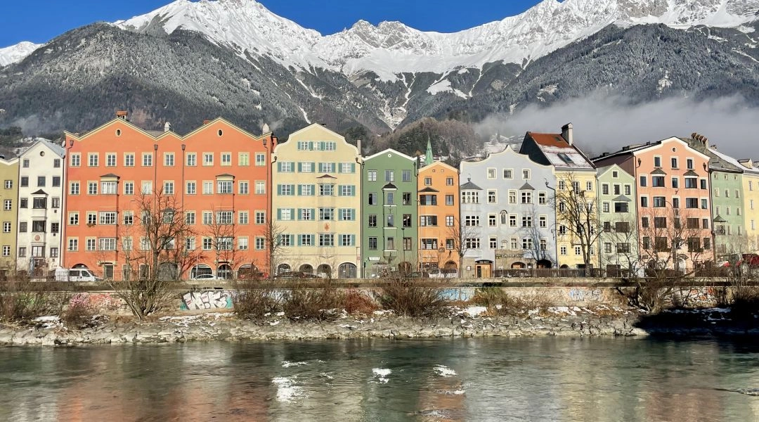 Kolorowe kamienice w Innsbrucku nad rzeką Inn, w tle ośnieżone góry