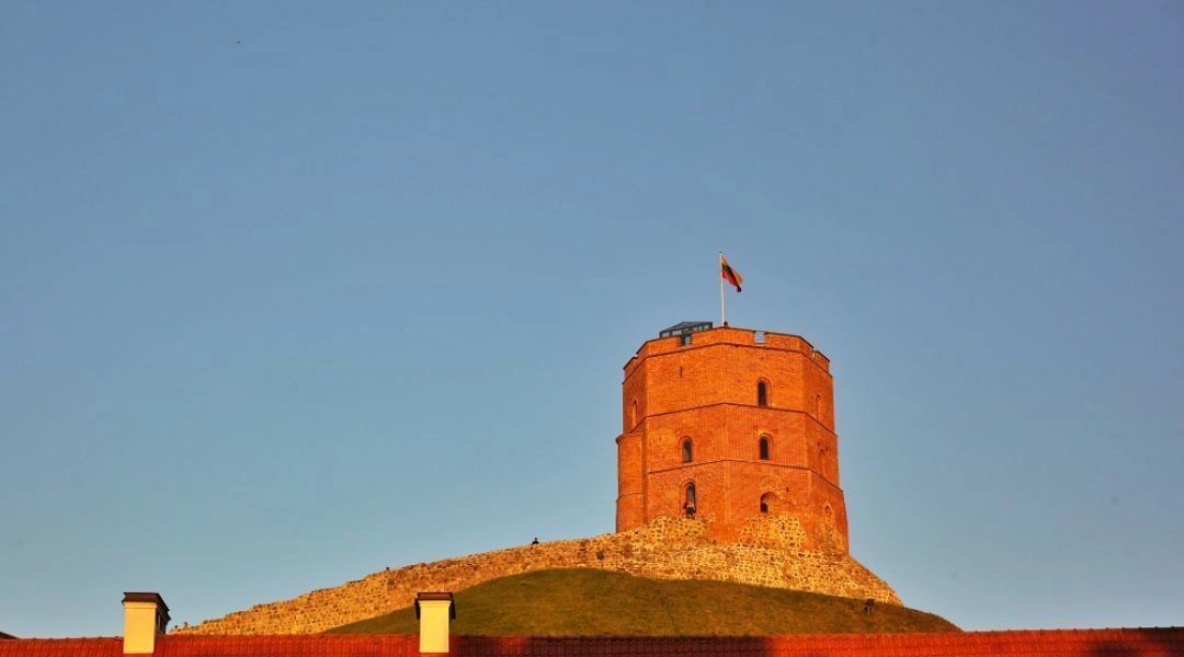 Ruiny zamku na Górze Giedymina w Wilnie, historyczna wieża górująca nad miastem o zachodzie słońca.