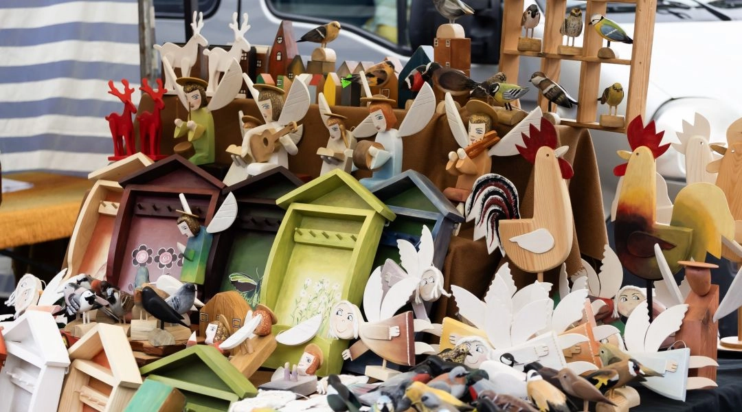 Drewniane anioły, ptaki i figurki ludowe na stoisku rękodzielniczym podczas jarmarku świątecznego w Warszawie.