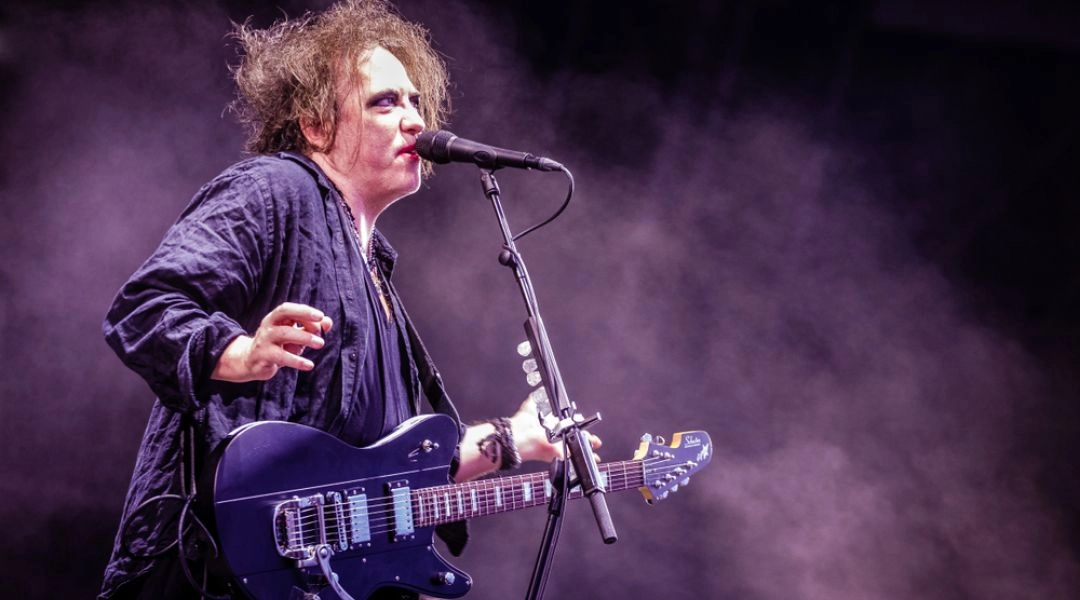 Wokalista z gitarą występuje na scenie podczas koncertu zespołu The Cure.