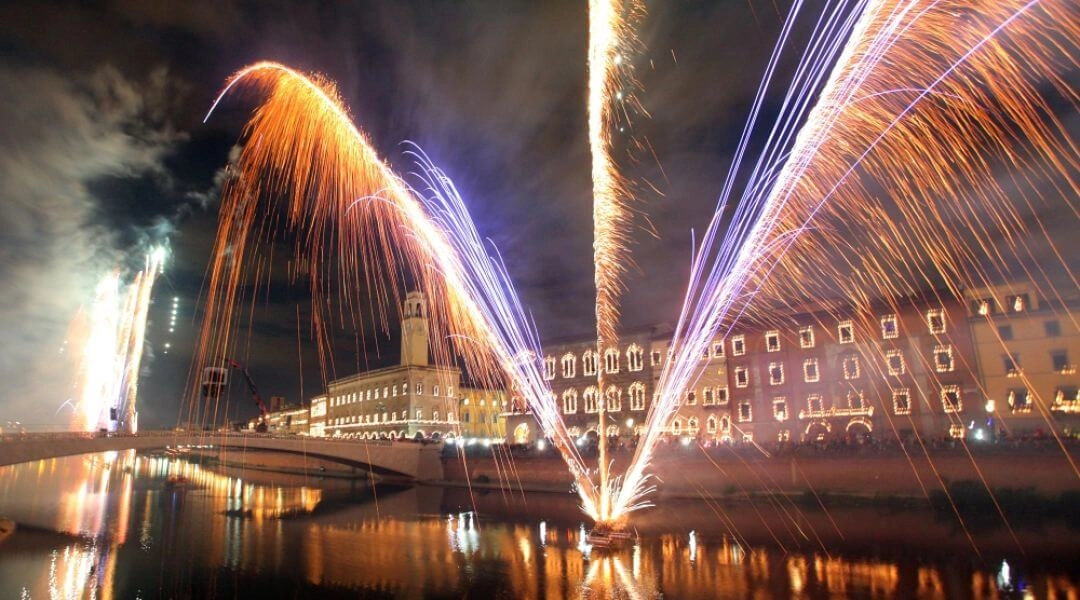 Kolorowe fajerwerki odbijają się w wodach rzeki Arno podczas Luminara di San Ranieri w Pizie.