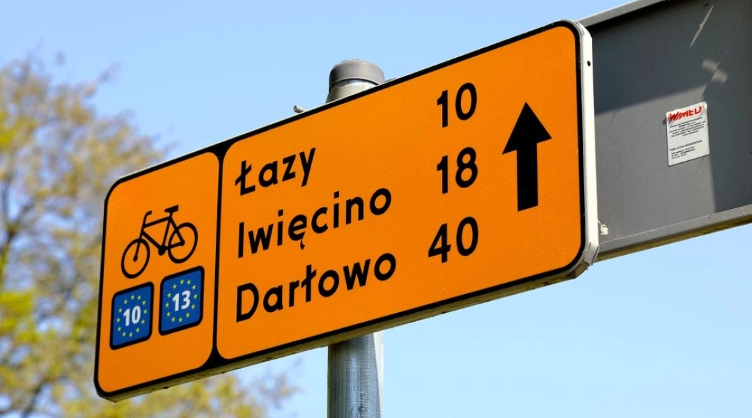 Drogowskaz trasy EuroVelo 10 i 13 wskazujący kierunek na Łazy, Iwięcino i Darłowo.