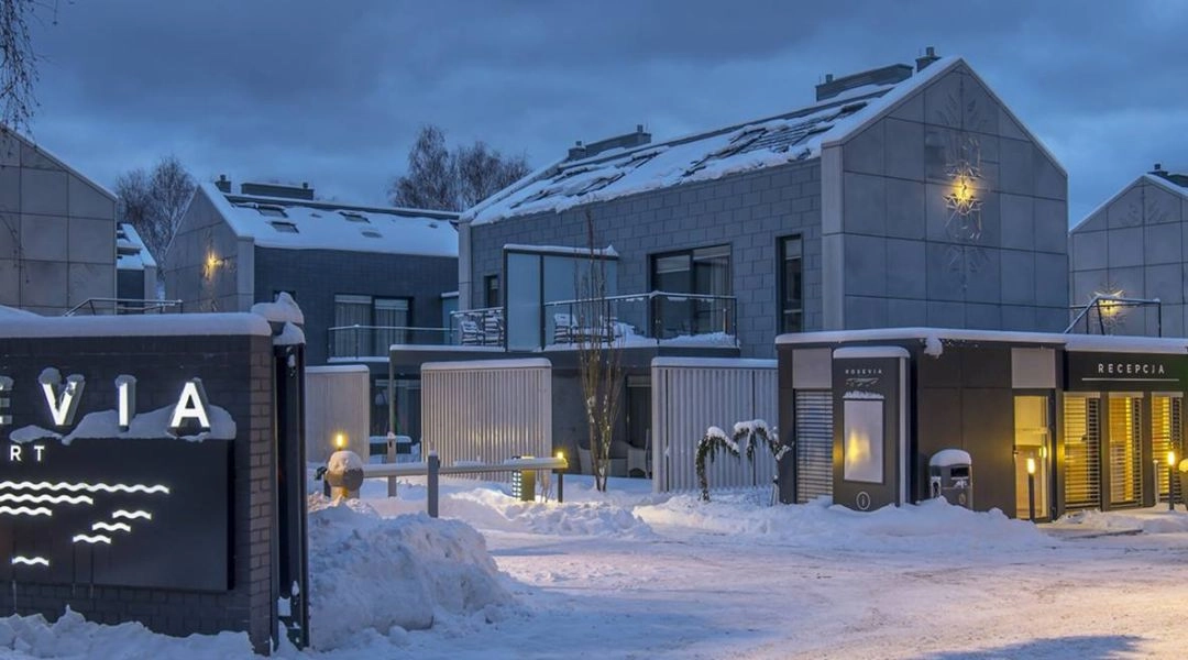 Rosevia Resort pokryta śniegiem, widok na nowoczesne budynki i wejście główne oświetlone zimowym wieczorem.