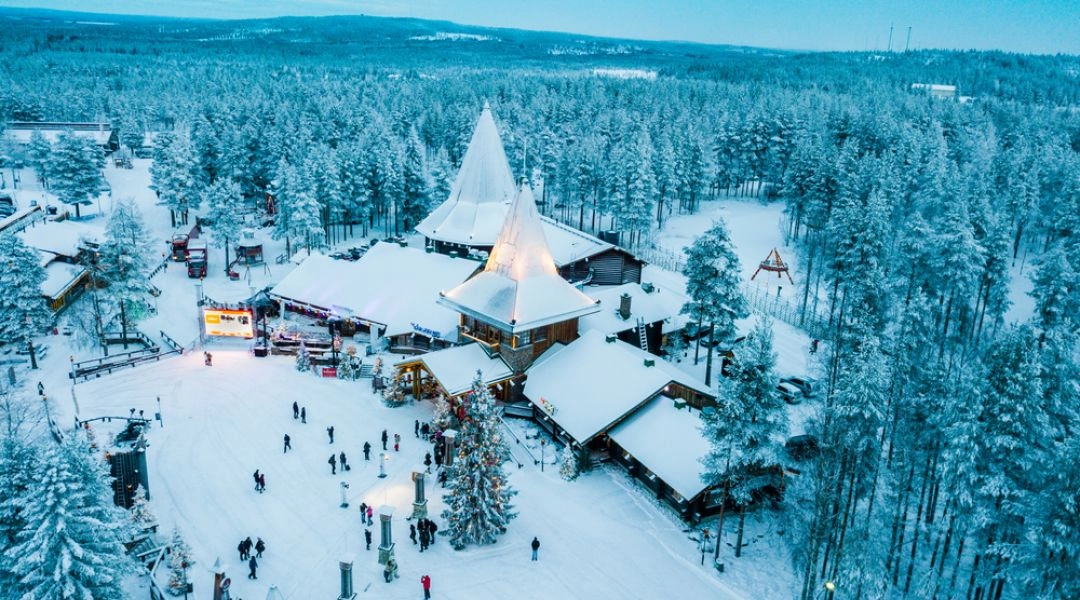 Widok z drona na Santa Claus Village w Rovaniemi otoczoną lasem i śniegiem.