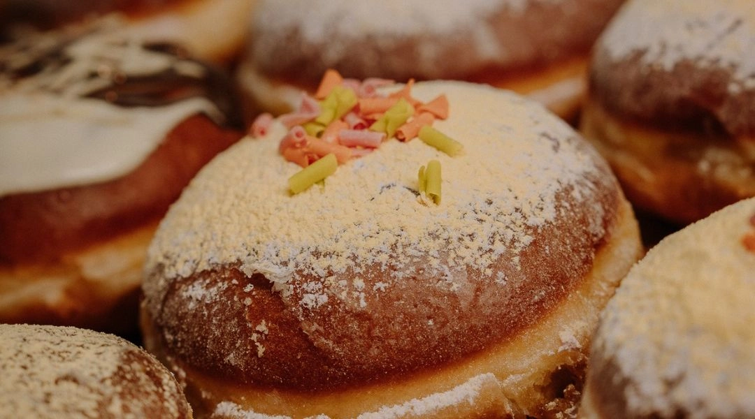 Kilka pączków z lukrem i kolorową posypką ułożonych blisko siebie