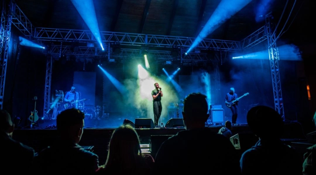 Koncert bluesowy na scenie w Suwałkach, z muzykami oświetlonymi niebieskimi reflektorami i publicznością przed sceną.