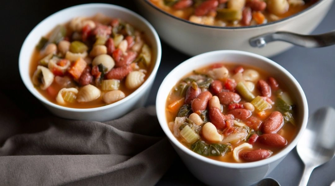 Minestrone z fasolą, ciecierzycą i warzywami w białych miskach, tradycyjna zupa Sardynii