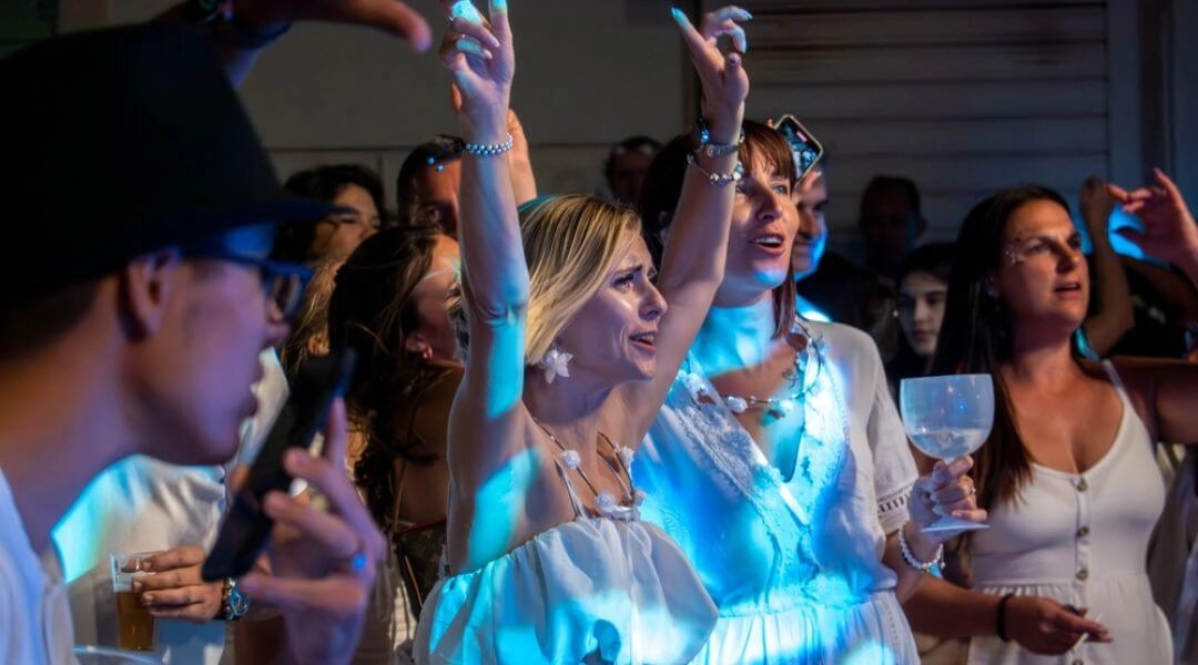 Ludzie bawiący się podczas sylwestra w Warszawie, kolorowe światła, tłum tańczących osób w nocnym mieście.