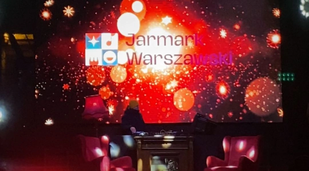 Scena Jarmarku Warszawskiego z dużym ekranem i dekoracjami świetlnymi podczas zimowego wydarzenia.