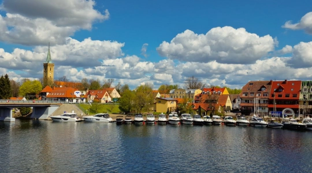 Mikołajki, most nad kanałem i port z jachtami, zabudowa miasteczka nad wodą.