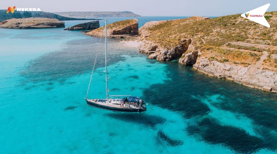 Błękitna Laguna na wyspie Comino, turkusowe morze i jacht zacumowany przy skalistym wybrzeżu Malty
