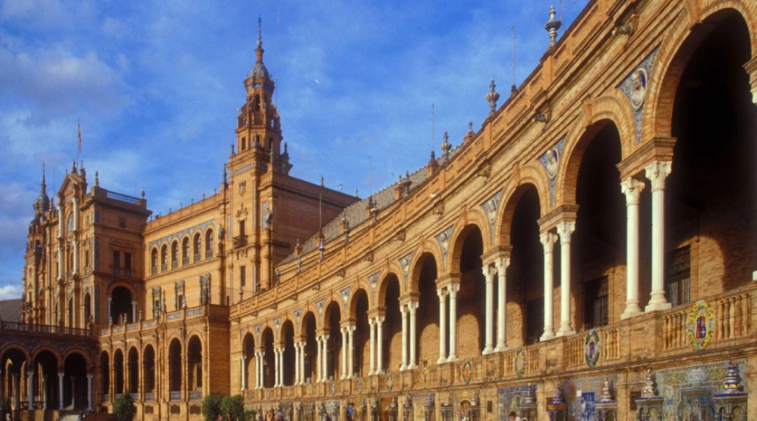 Arkady i półkolista zabudowa Placu Hiszpańskiego w Sewilli w ciepłym popołudniowym świetle.