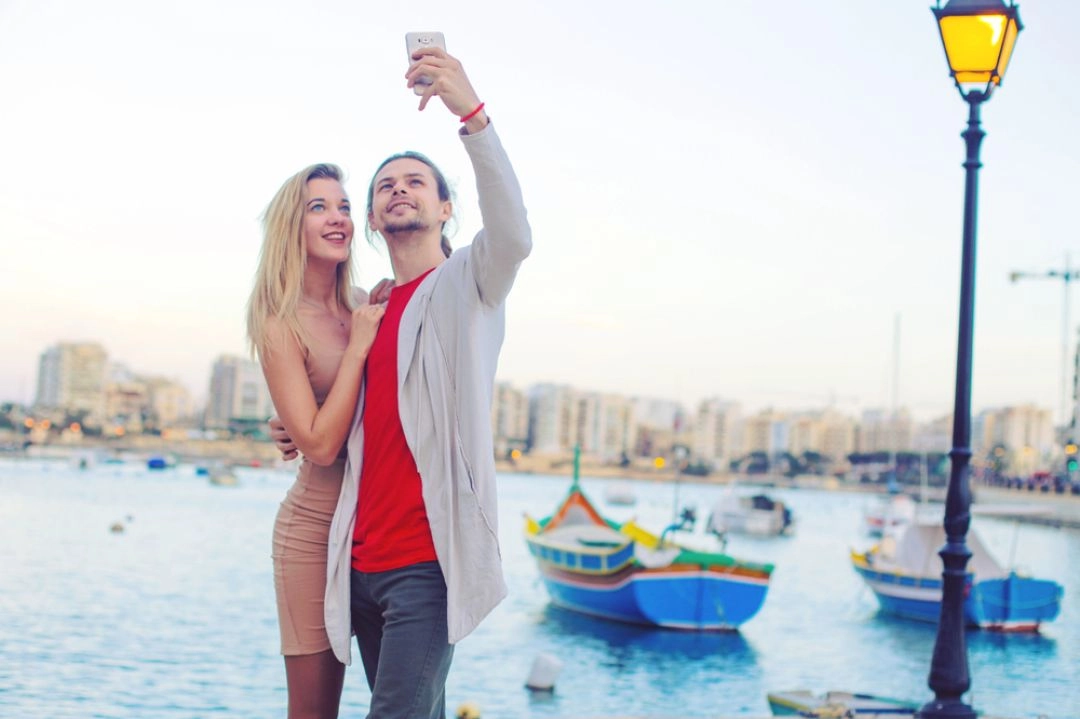Marsaxlokk Malta kolorowe łodzie luzzu romantyczny spacer pary zakochanych, którzy robią sobie selfie