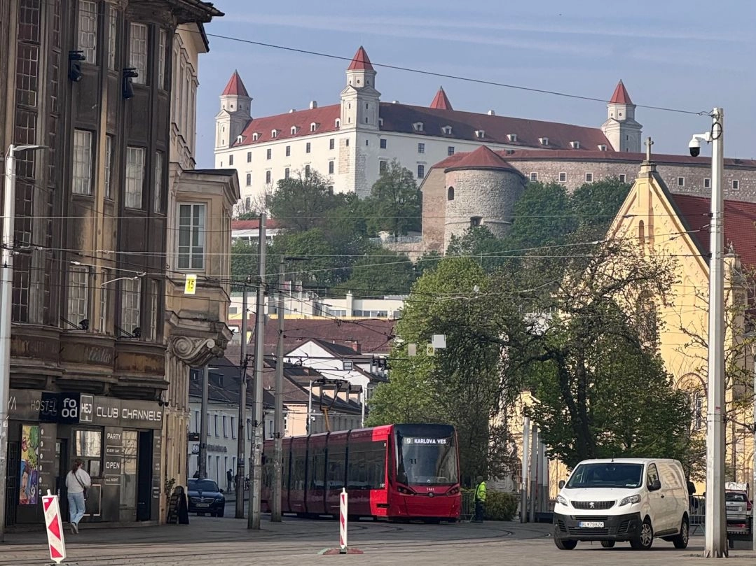 Widok na Zamek Bratysławski, tramwaj i miejską zabudowę słowackiej stolicy w słoneczny dzień.