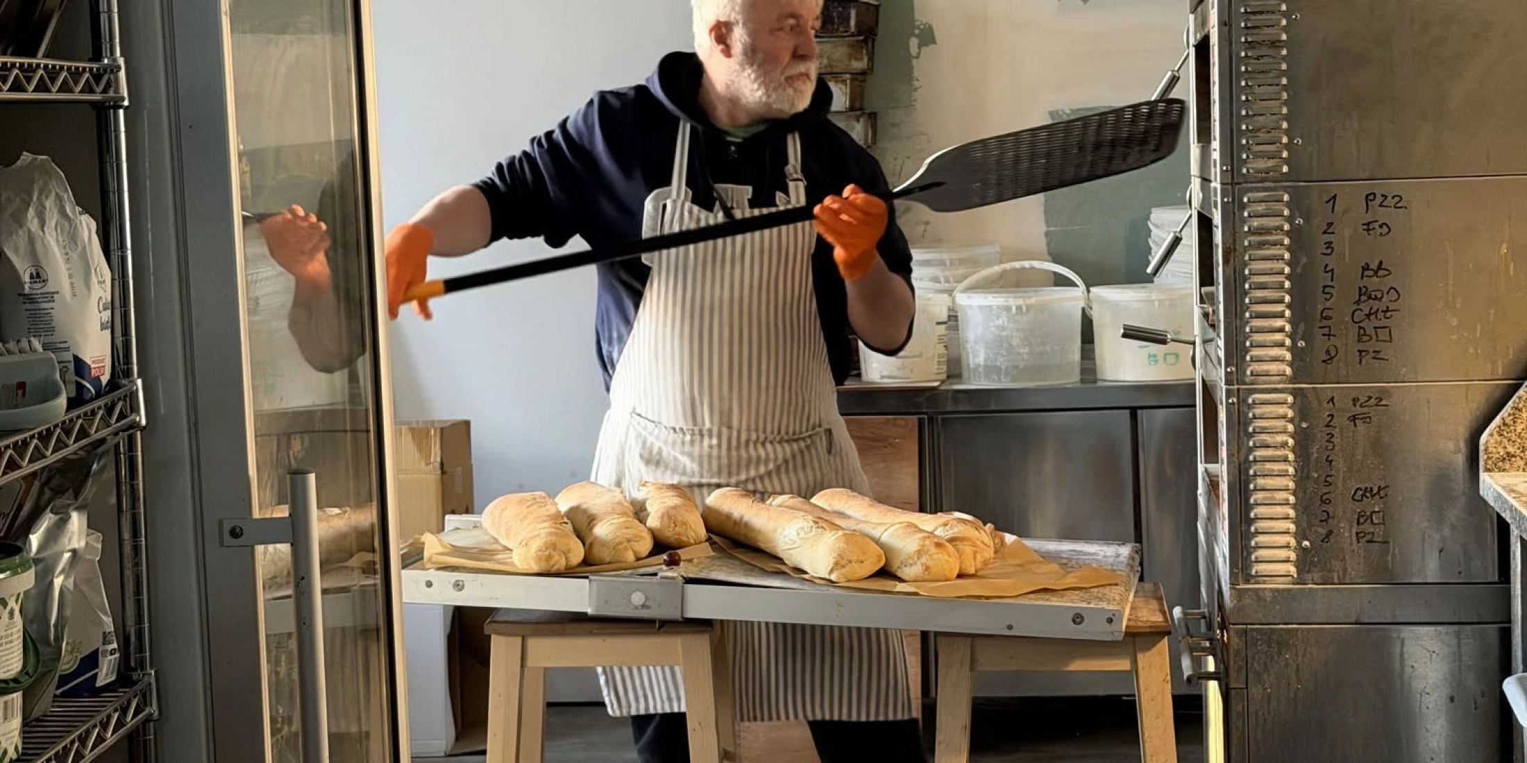 Piekarz i właściciel wyjmuje świeże pieczywo z pieca w krakowskiej piekarni 100bochenków
