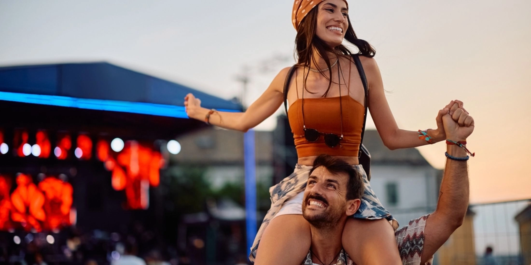 Uśmiechnięta para bawi się podczas letniego festiwalu plenerowego przy scenie koncertowej.