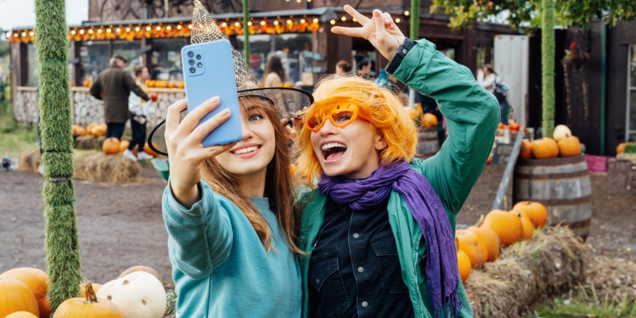 Dwie kobiety robią selfie wśród dyń i jesiennych dekoracji na farmie dyniowej