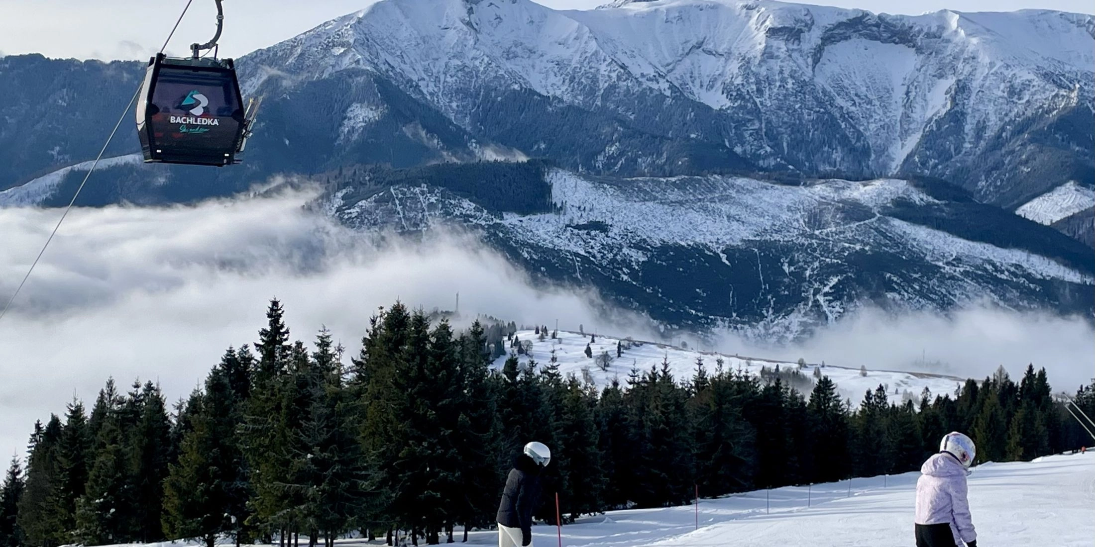 Narciarze na trasie zjazdowej w ośrodku Bachledka Ski & Sun z widokiem na Tatry.