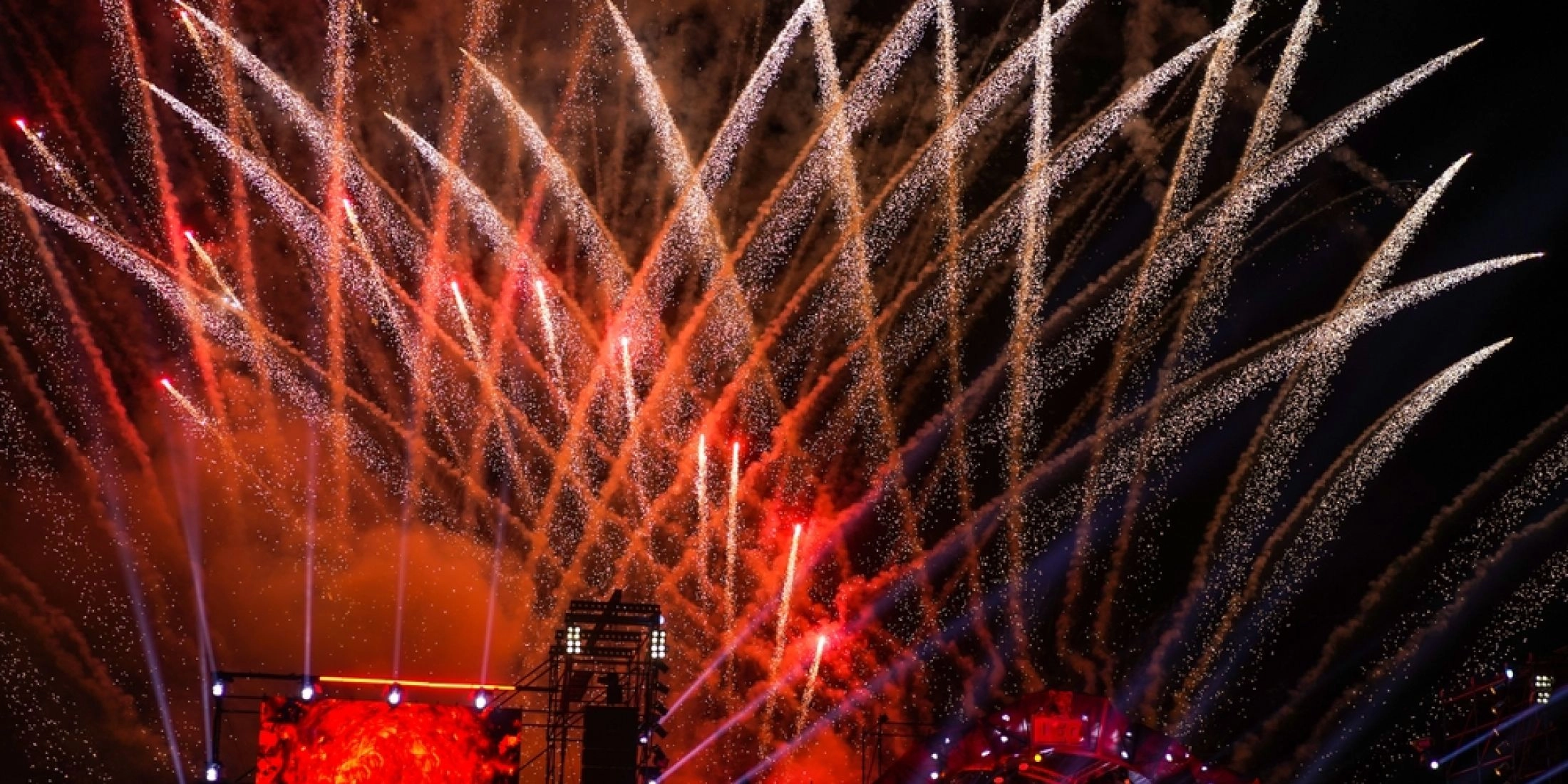 Plenerowy koncert sylwestrowy nocą, scena muzyczna i pokaz fajerwerków nad tłumem uczestników.