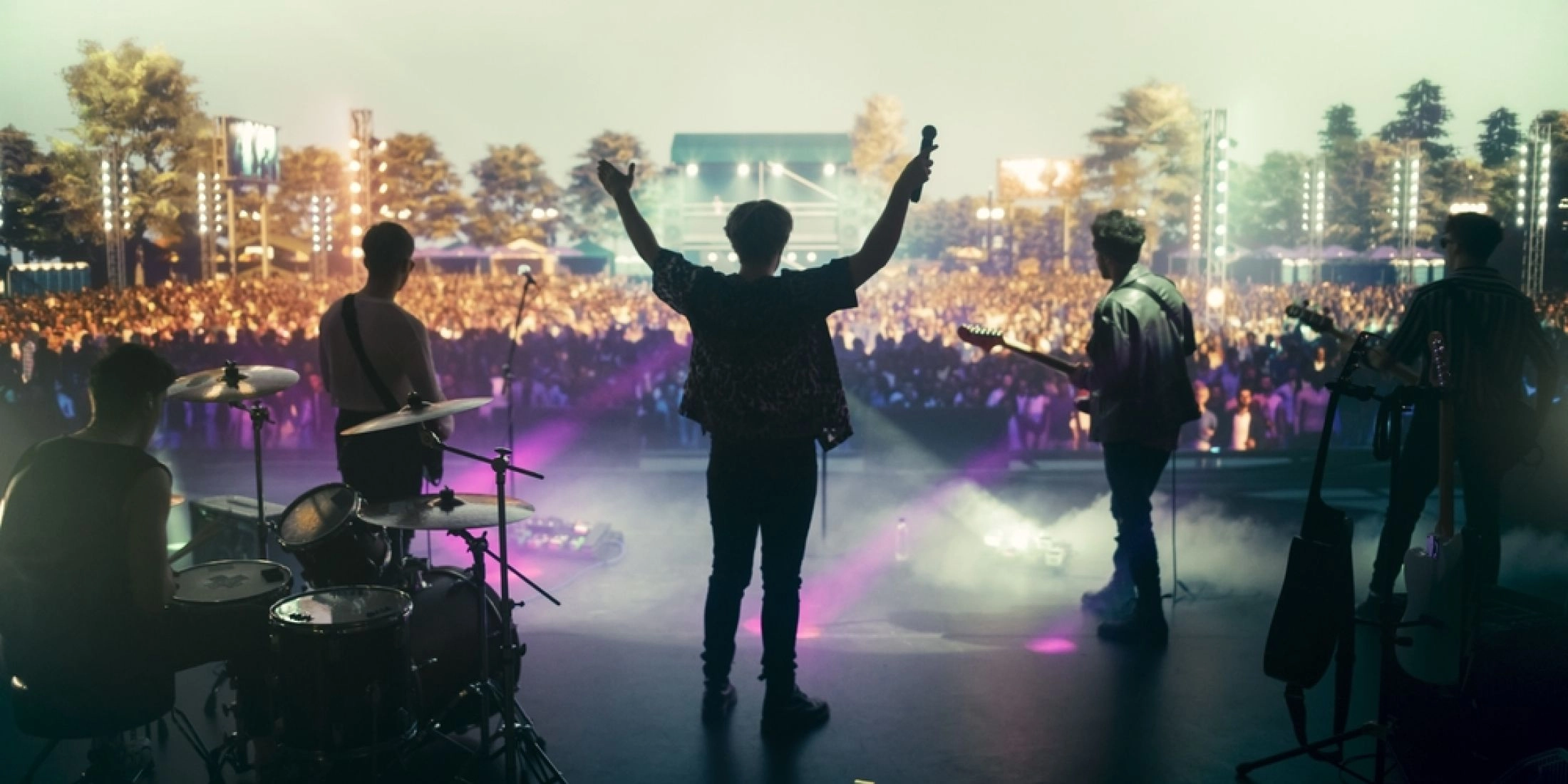 Zespół na scenie podczas plenerowego koncertu, przed sceną tłum publiczności