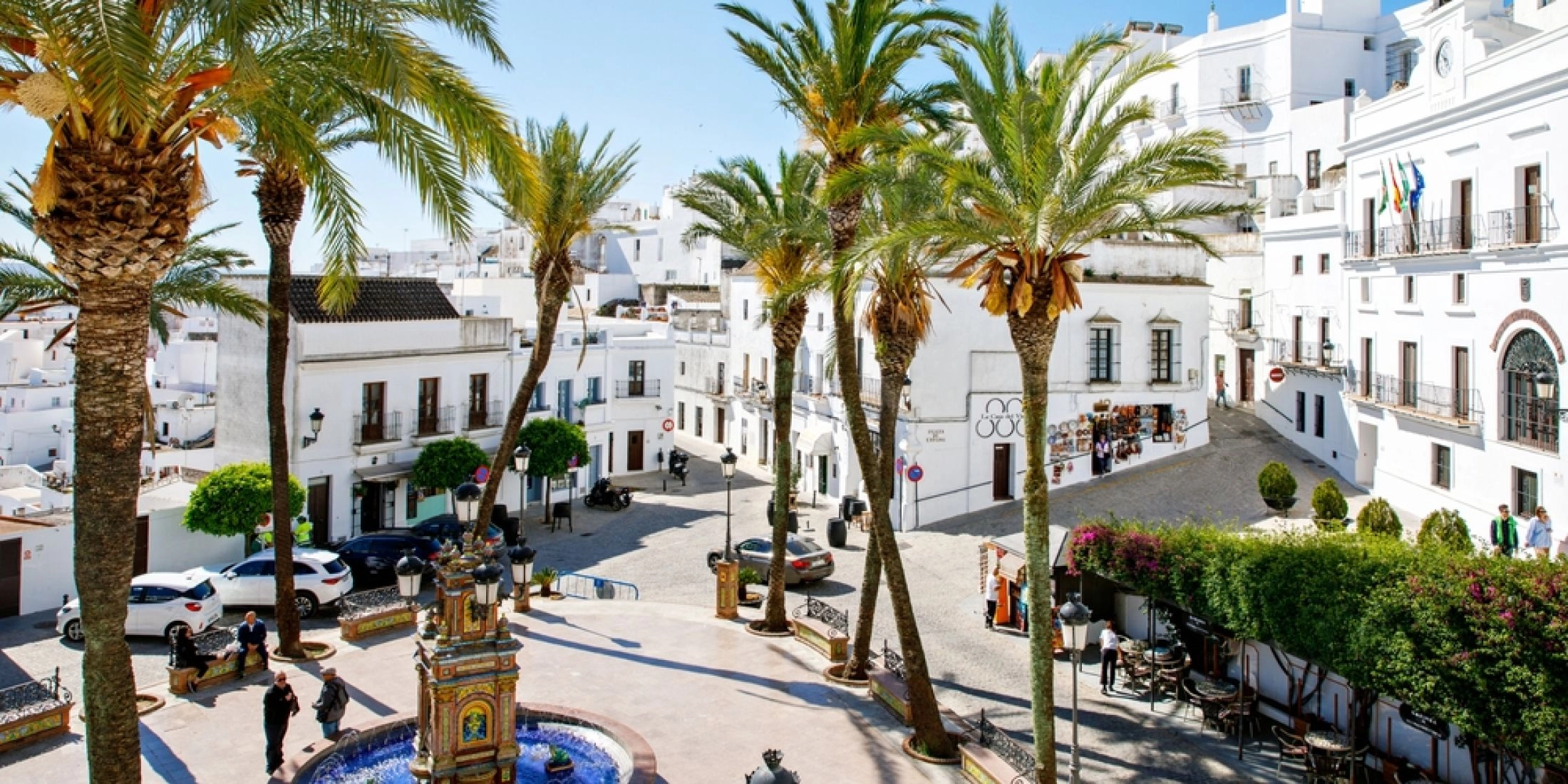 Plac z ceramiczną fontanną, palmami i białymi domami w Vejer de la Frontera w Andaluzji.