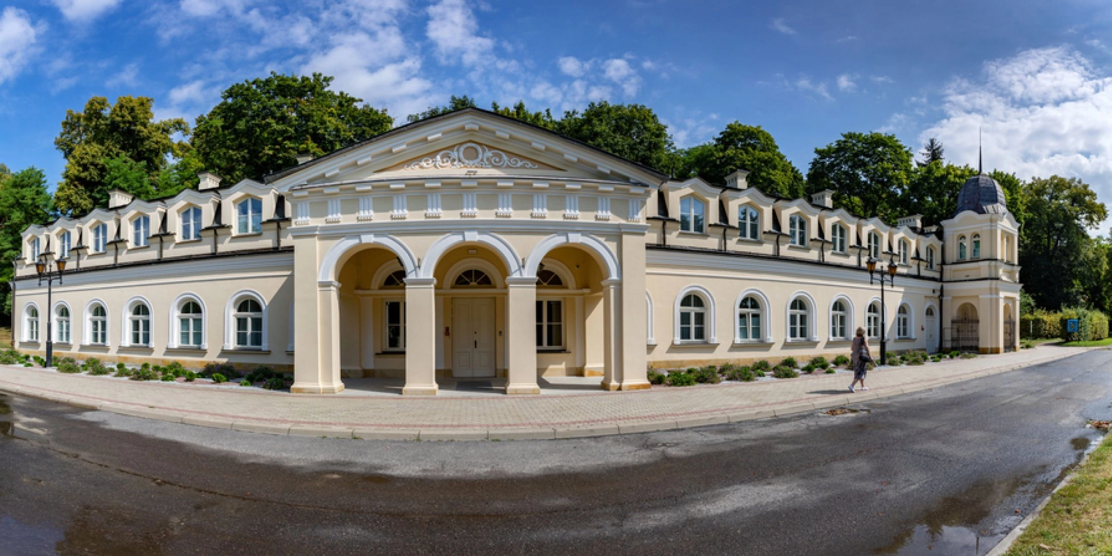 Jasna, rozległa fasada Sanatorium Książę Józef w Parku Zdrojowym w Nałęczowie z arkadowym wejściem i narożną wieżyczką.