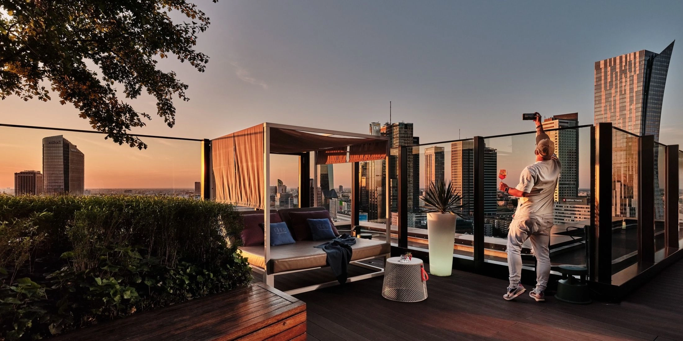 Taras Ether Rooftop Bar w Warszawie z widokiem na wieżowce centrum miasta o zachodzie słońca.