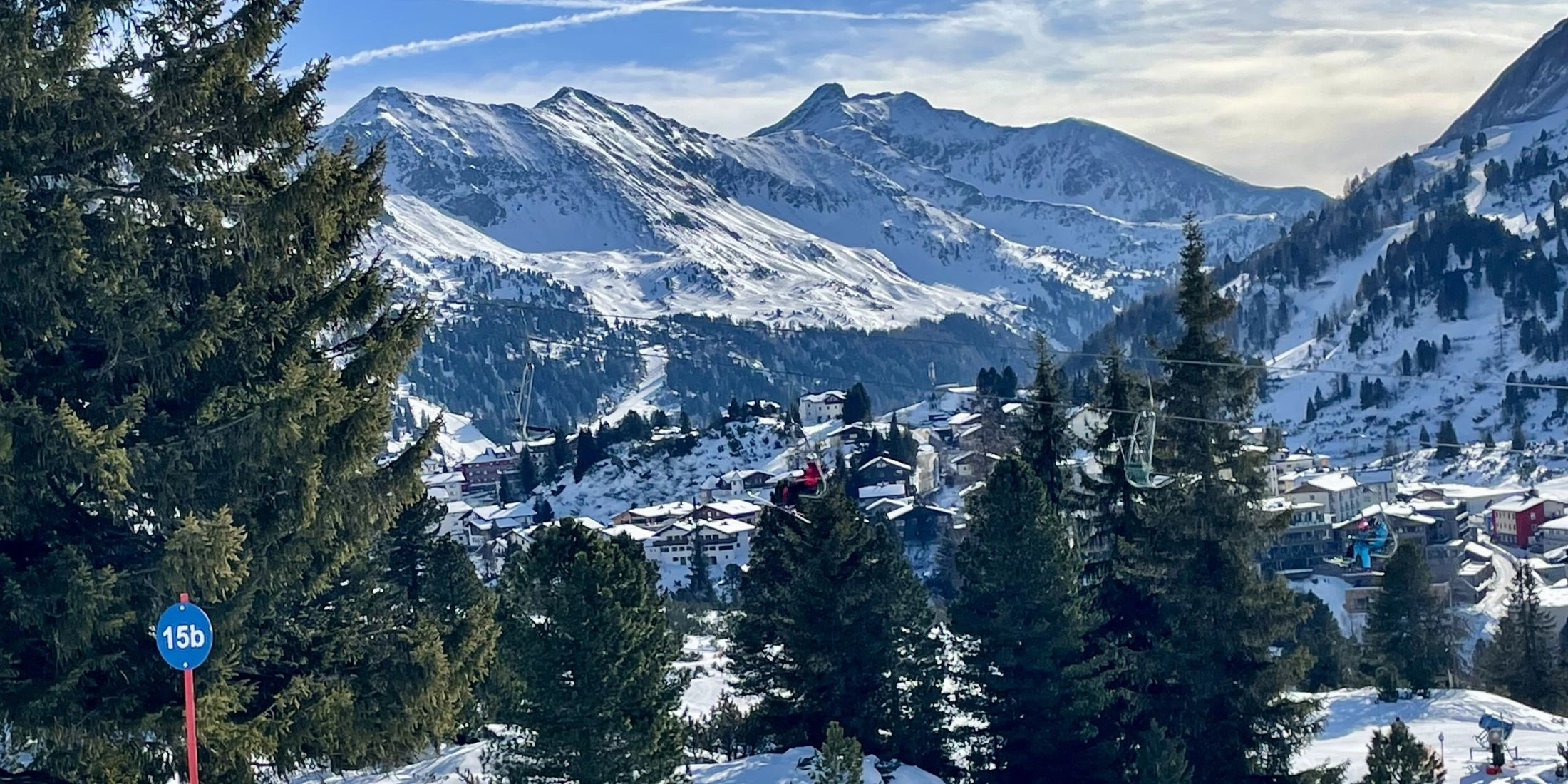 Widok na miejscowość Obertauern z trasy narciarskiej, oznaczenie 15b i alpejska panorama w tle