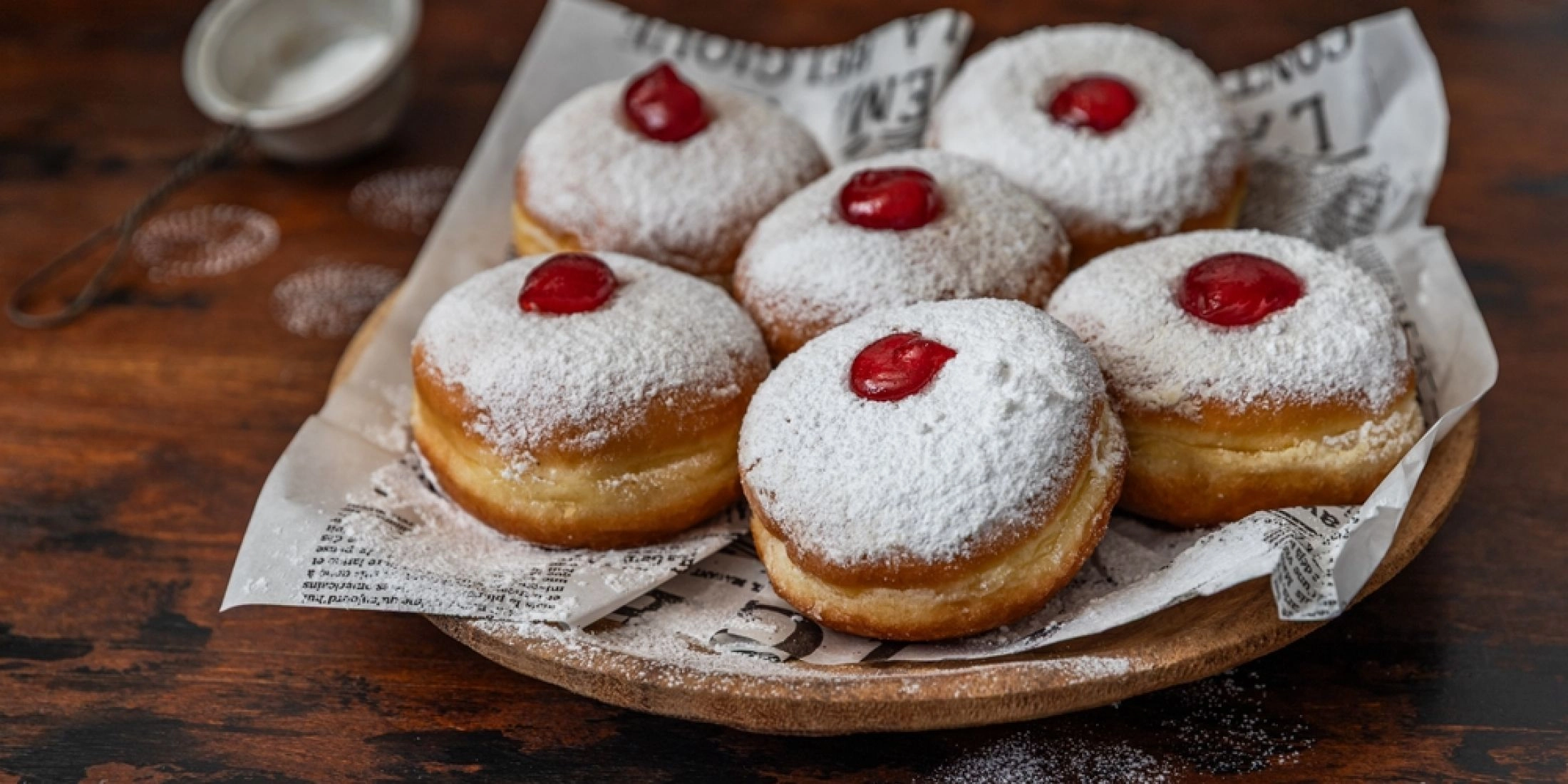 Tradycyjne pączki z różą posypane cukrem pudrem na drewnianym stole