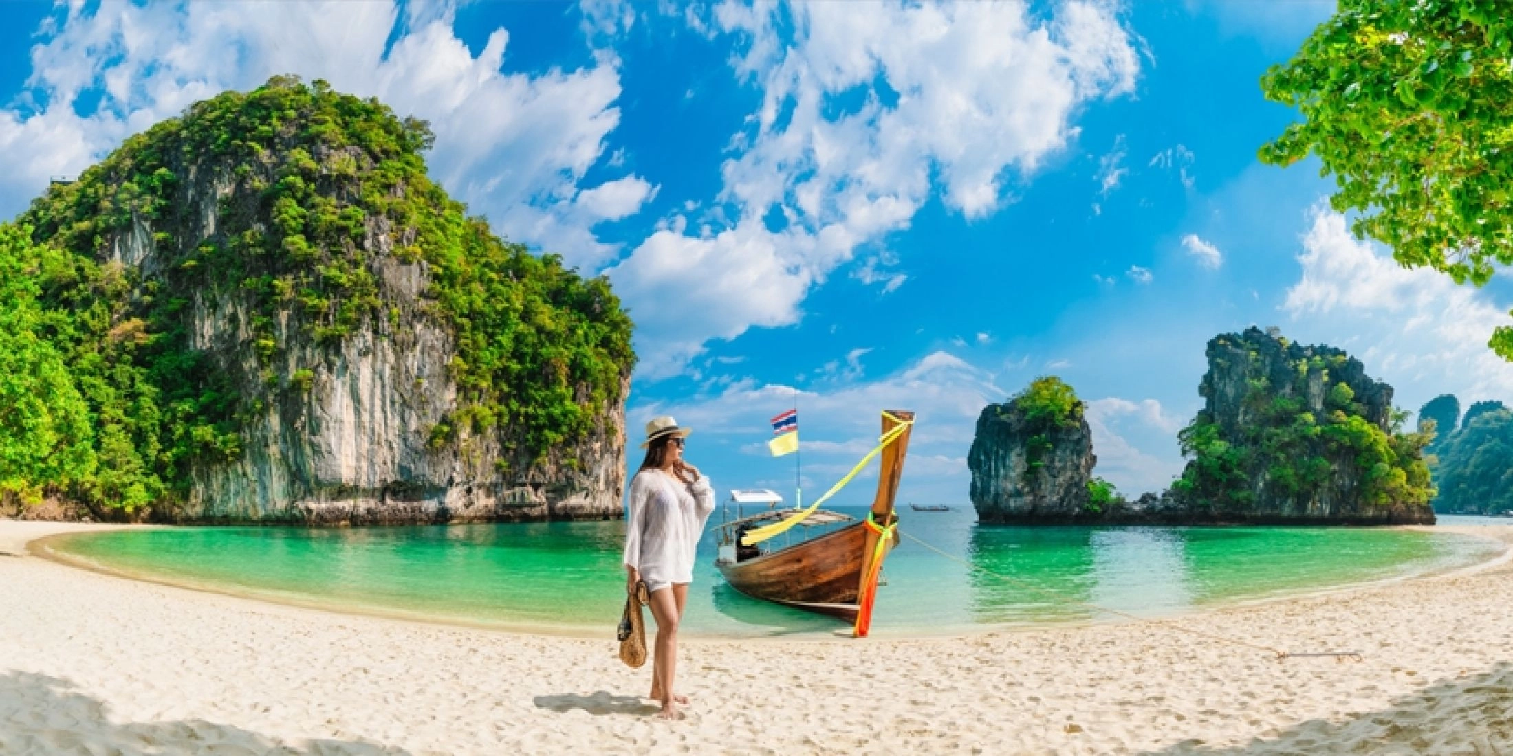 Kobieta na piaszczystej plaży obok tradycyjnej tajskiej łodzi, turkusowa woda i wapienne wyspy Phuket