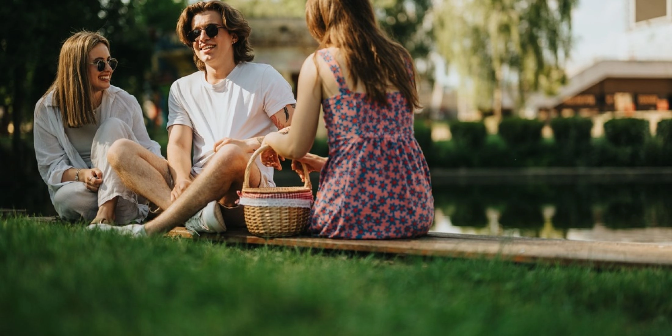 Piknik na trawie w parku pod Warszawą troje przyjaciół siedzi na kocu na trawie z koszykiem
