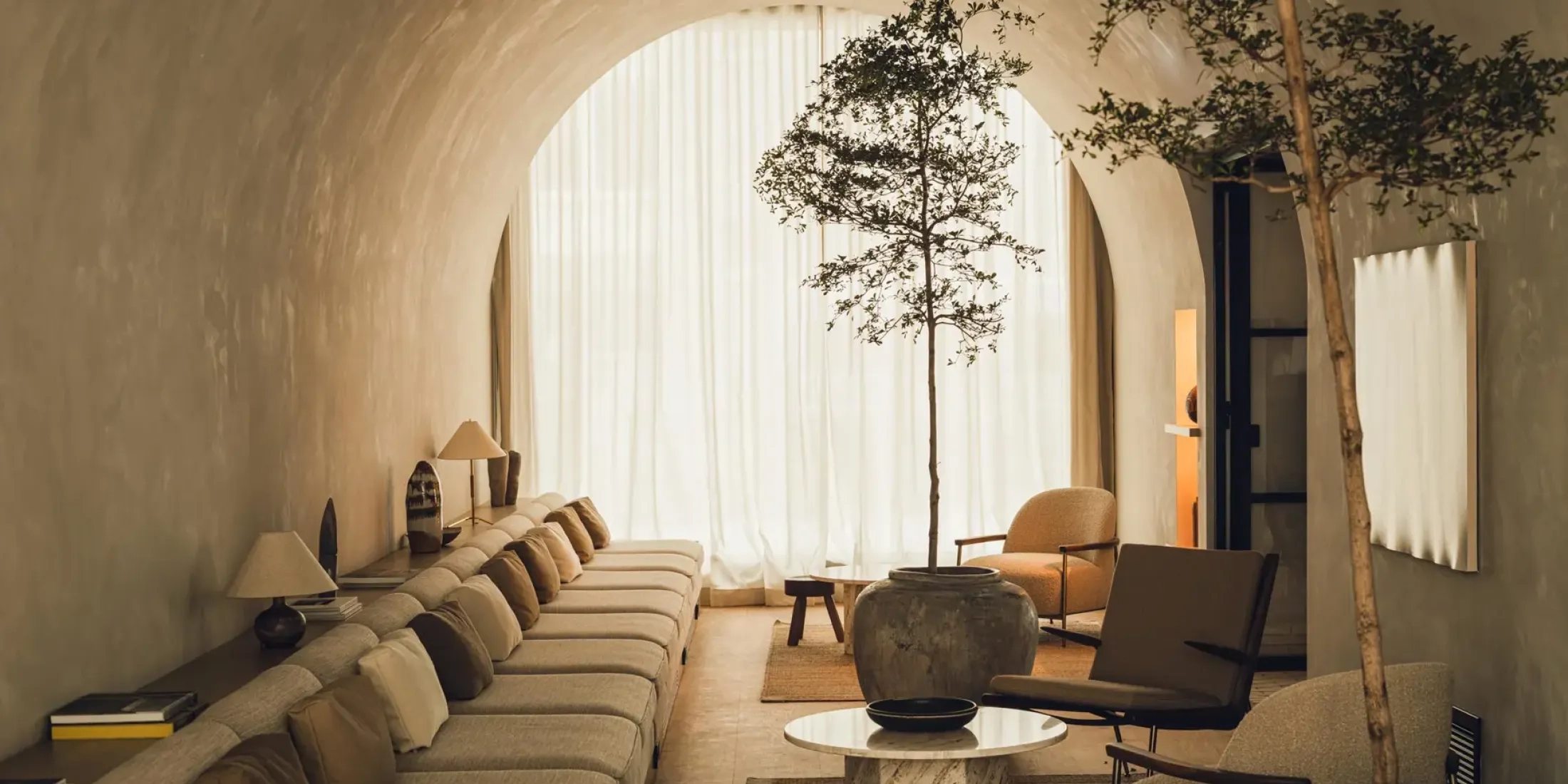 Strefa lounge w hotelu PURO Warszawa Stare Miasto z długą sofą, fotelami i drzewem w donicy, projekt wnętrz GamFratesi