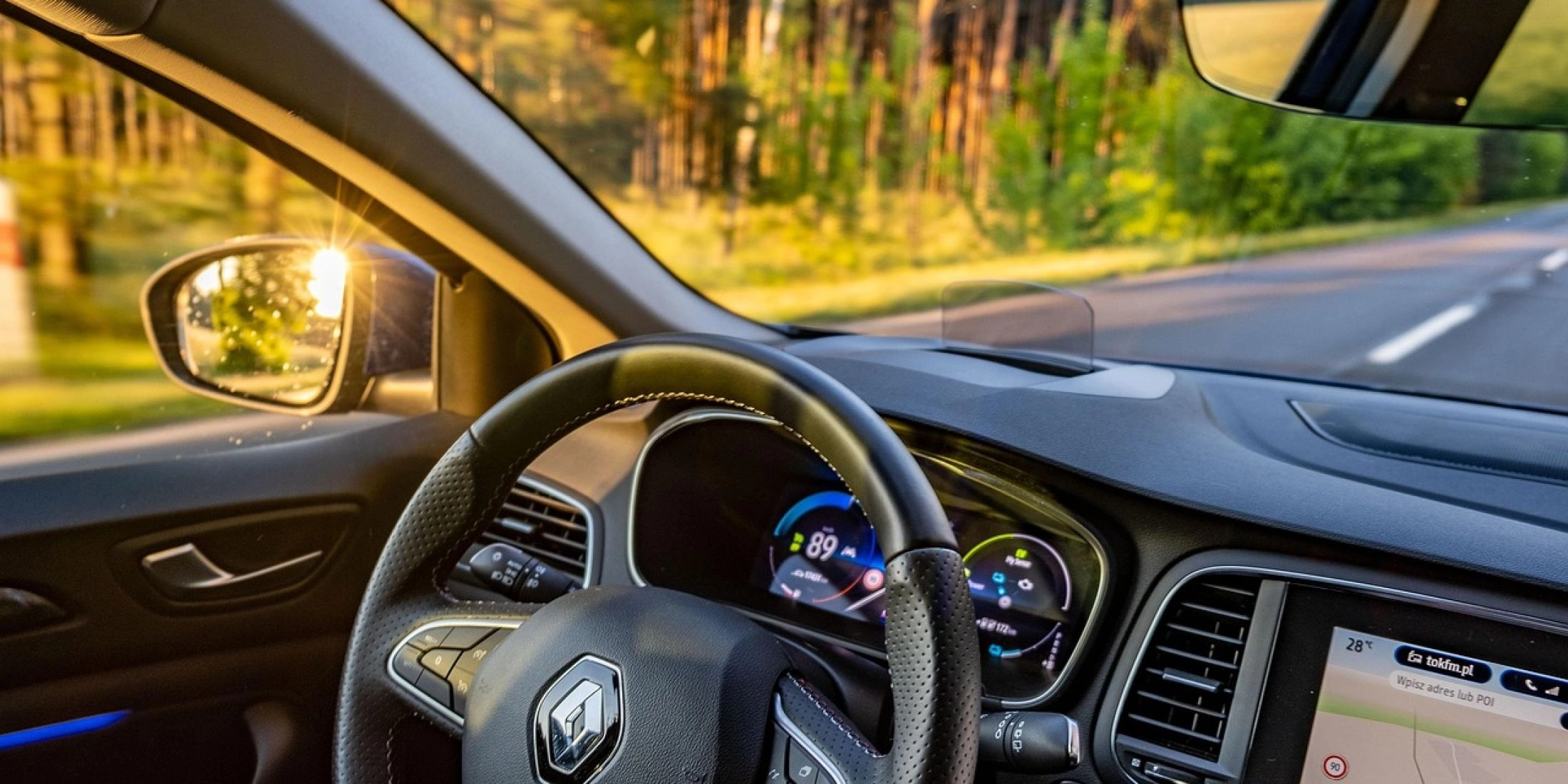 Wnętrze samochodu renault clio z widokiem na kierownicę i przednia szybę