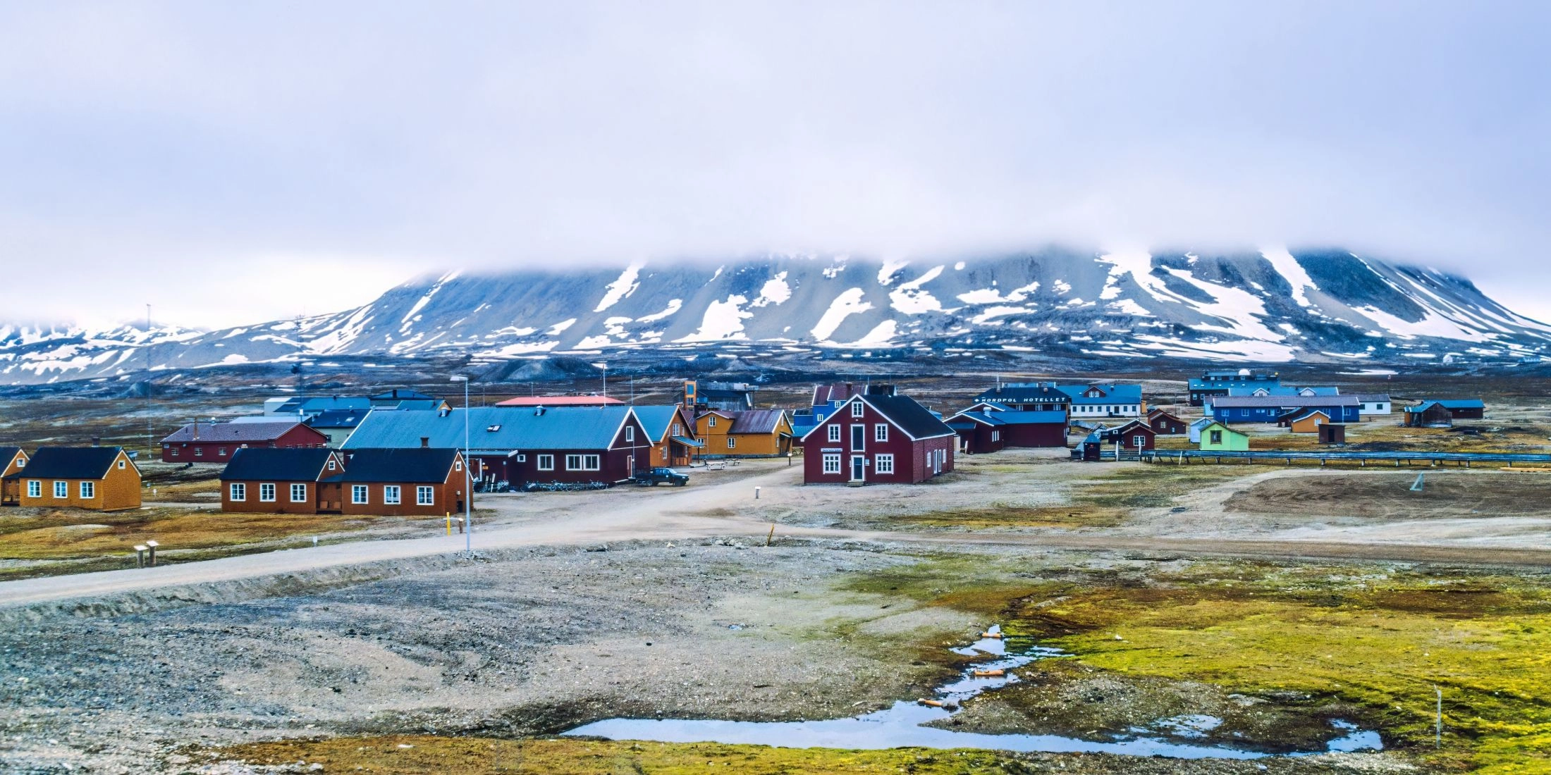 Kolorowe zabudowania Longyearbyen na Svalbardzie z ośnieżonymi górami w tle.