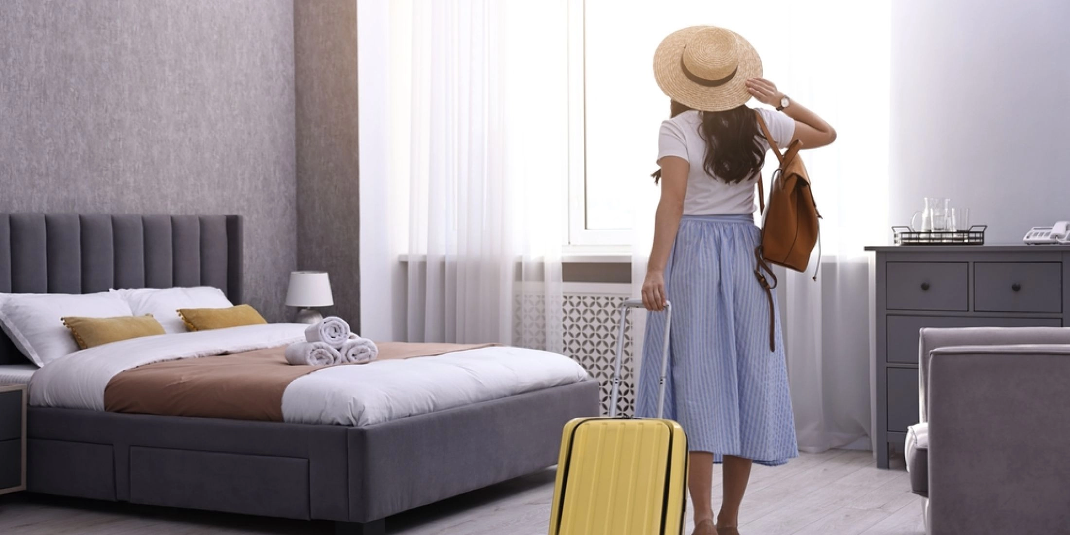 Kobieta z walizką w pokoju hotelowym podczas wakacyjnego wyjazdu