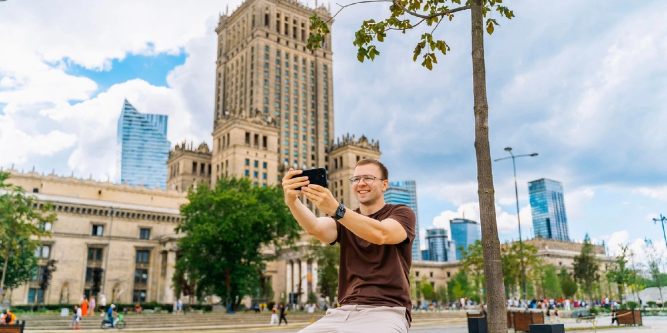 Mężczyzna robiący zdjęcie telefonem przed Pałacem Kultury i Nauki w Warszawie