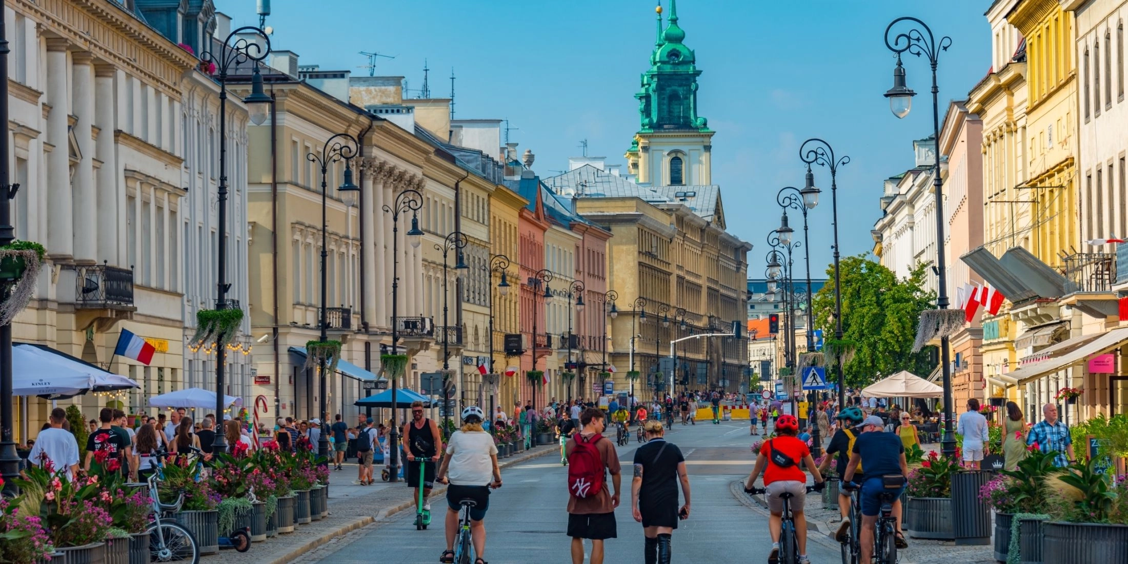 Wiosenne centrum Warszawy, spacerowicze i rowerzyści na jednej z ulic w weekend.