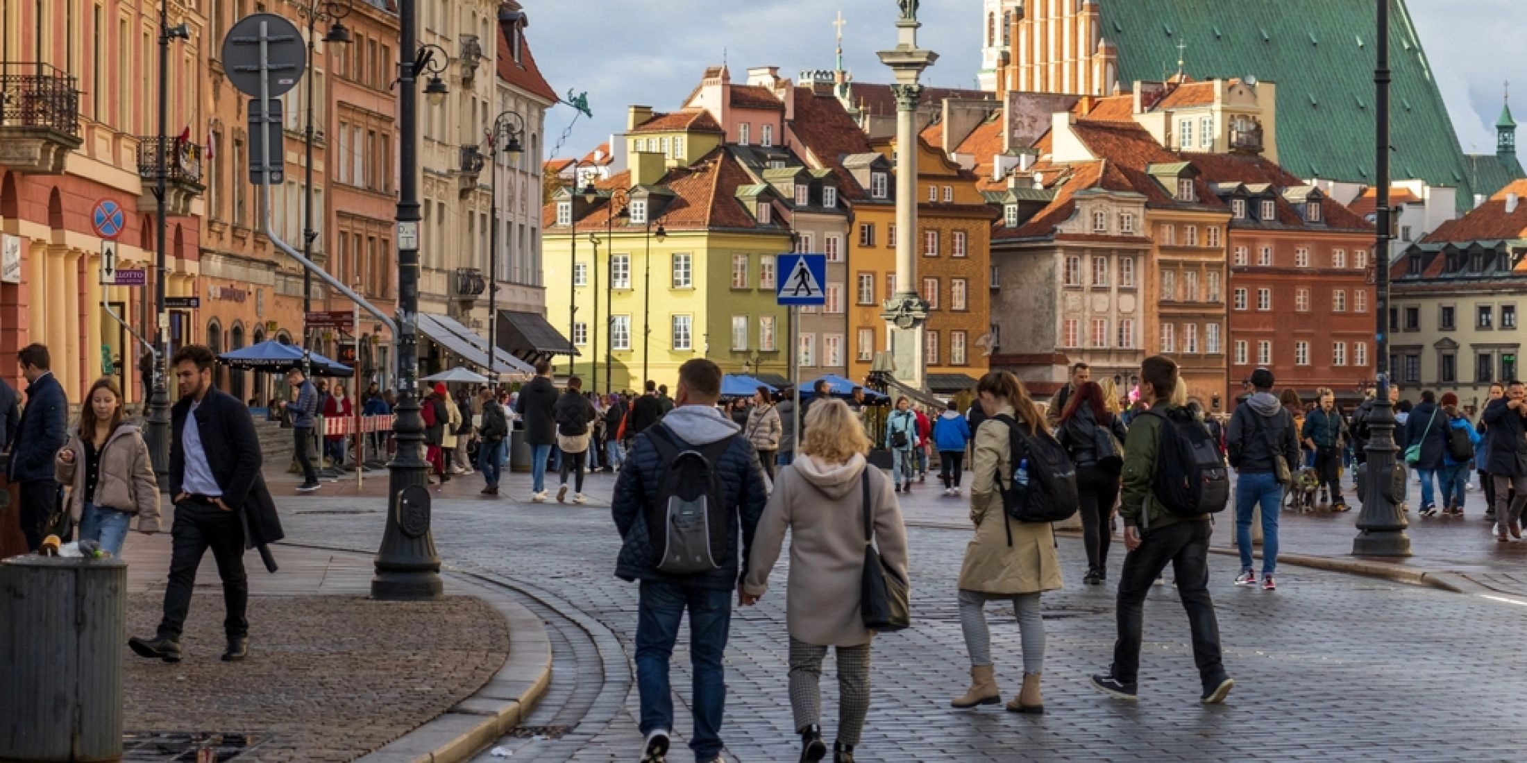 pacerowicze na Starym Mieście w Warszawie, w tle kolorowe kamienice i kościół św. Anny