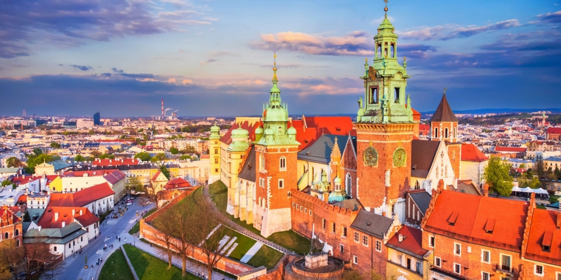Panorama Wawelu w Krakowie z katedrą, zamkiem królewskim i zabudową Starego Miasta w świetle zachodzącego słońca.