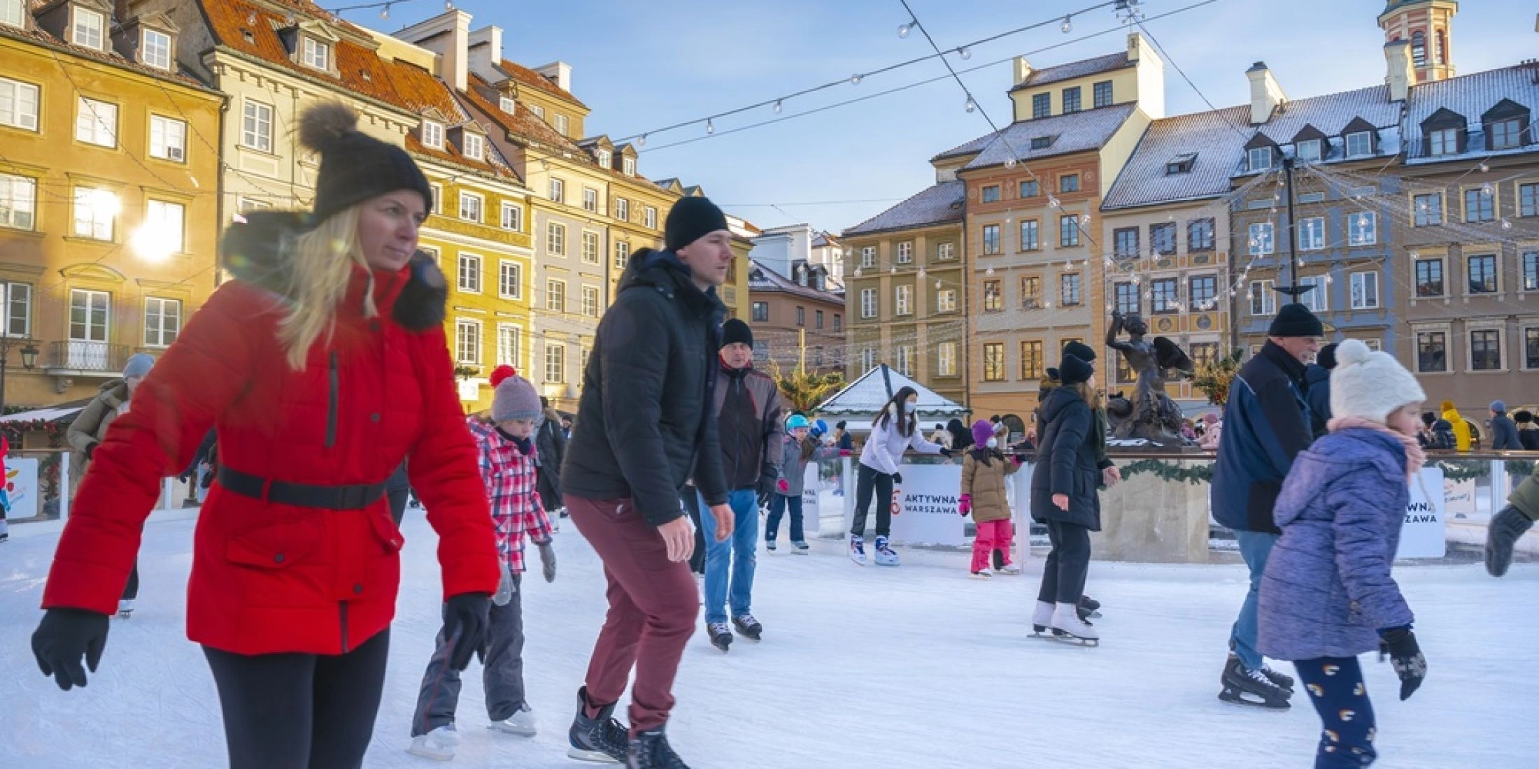 Ludzie jeżdżący na łyżwach na lodowisku w centrum Warszawy zimą.